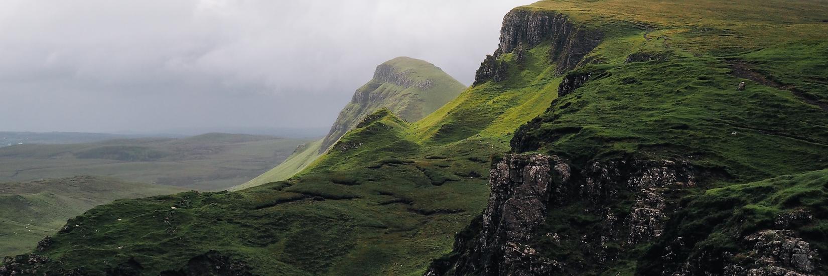 Green hills and rock faces under a grey sky
